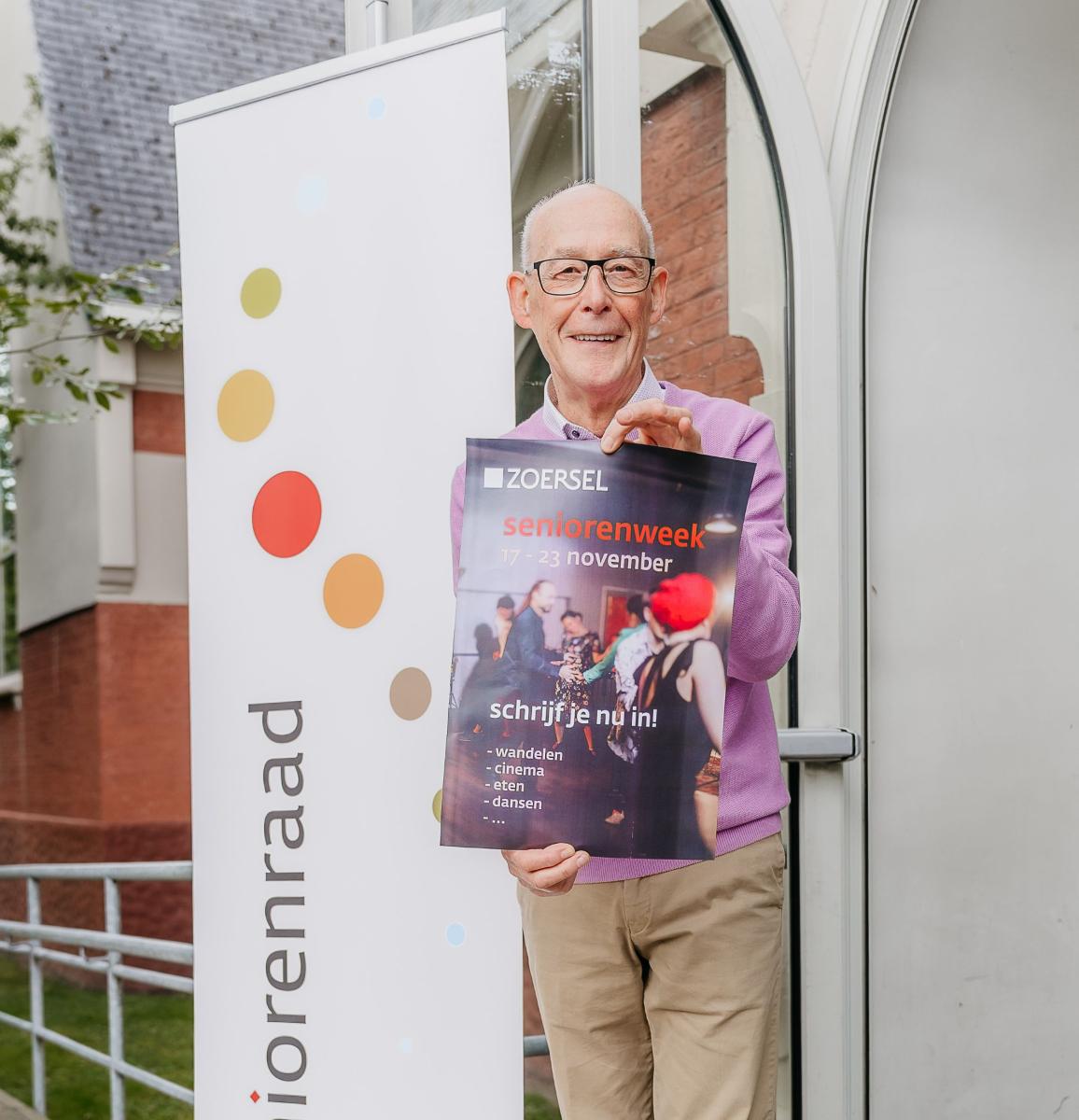 Jef Van der Linden van de seniorenraad houdt een affiche in de hand en spoort senioren aan om in te schrijven voor de seniorenweek.