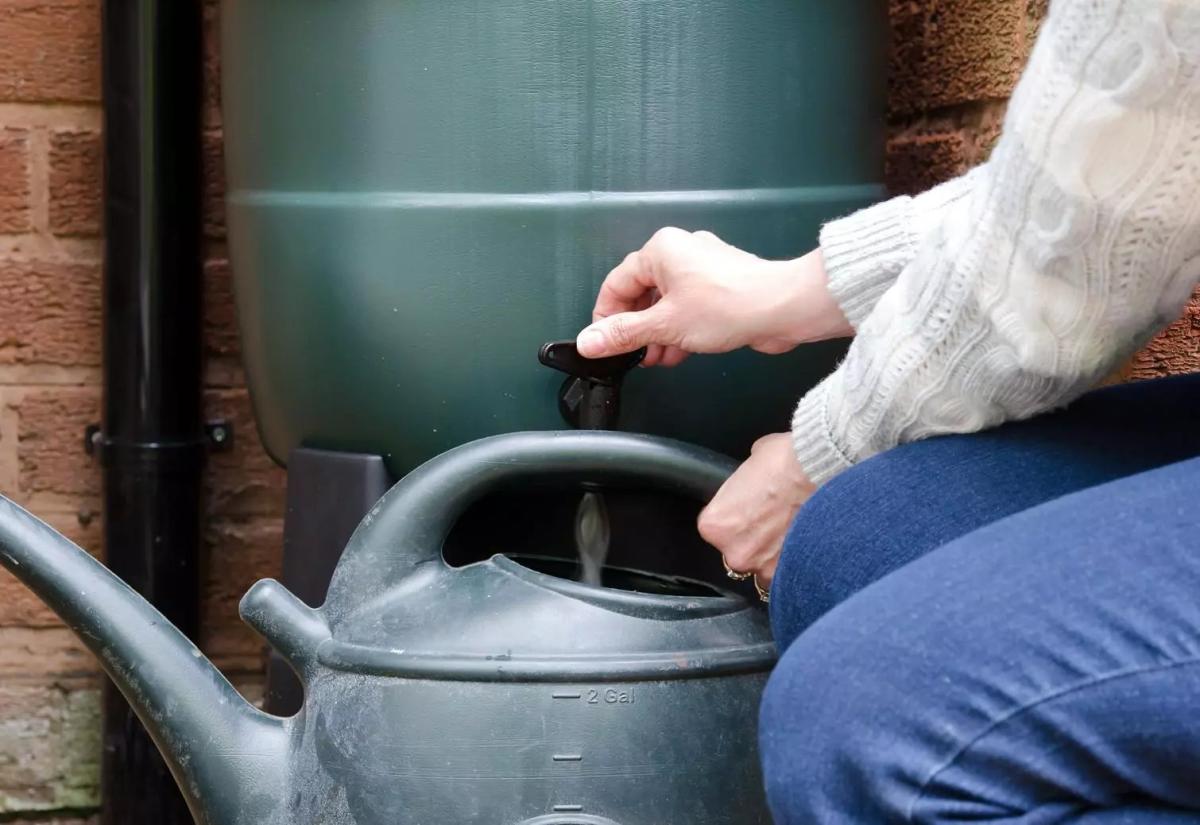 gieter vullen met regenwater uit regenton