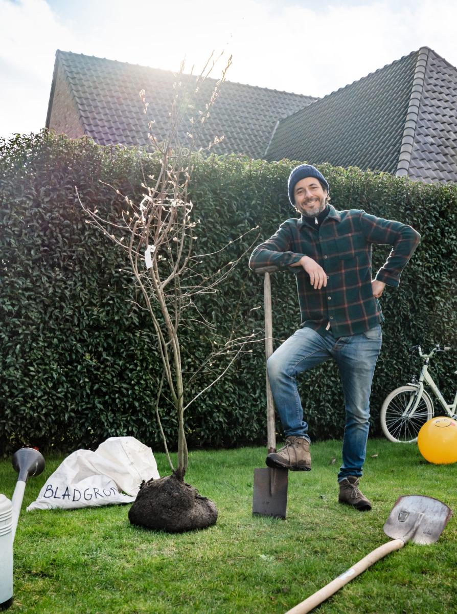 Dieter Coppens leunt op zijn spade, klaar om een boom in de grond te planten.
