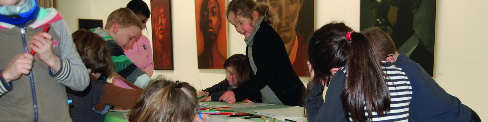 Kinderen die in de Bijl aan het tekenen zijn. Op de achtergrond hangen er schilderijen.