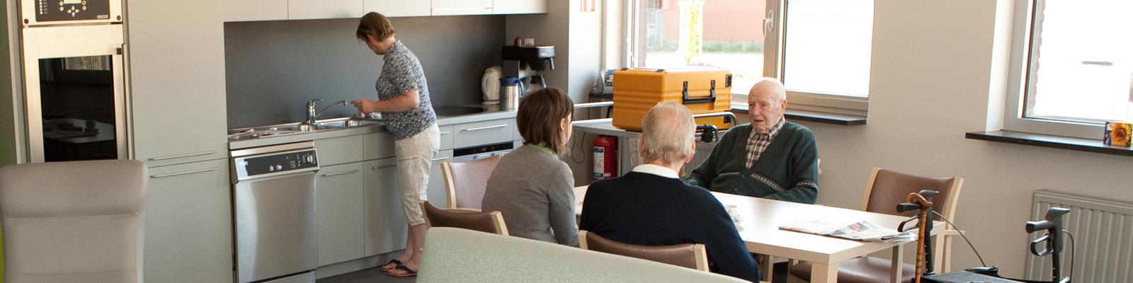 ouderen die gezellig tafelen in de keuken van het woonzorgcentrum