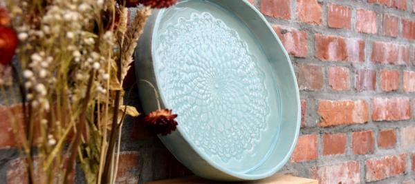 Eén ronde schaal in klei met een decoratieve afdruk.