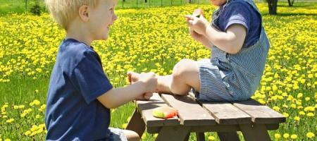twee kinderen pickinicken op een bankje in de buurt