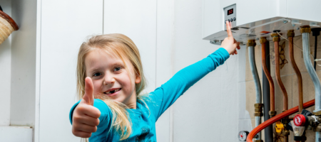 een meisje zet de temperatuur van de verwarmingsketel op 50 graden en steekt haar duim omhoog