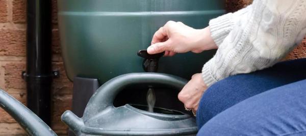 gieter vullen met regenwater uit regenton