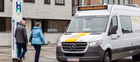 een man en een vrouw stappen aan een Hoppinpunt op een De Lijn Flex bus