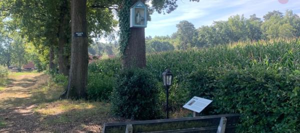 een foto van een bank aan een kapelletje, op een rustige plek. 