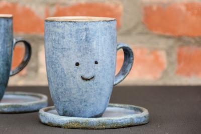 Koffietas in klei , blauwe glazuur met een smiley 