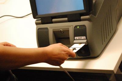 een persoon steekt zijn of haar kieskaart in de stemcomputer