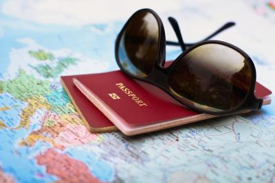 zonnebril ligt op een internationaal paspoort en een wereldkaart