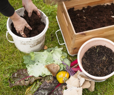 een persoon zit met zijn handen te voelen in een bak compost