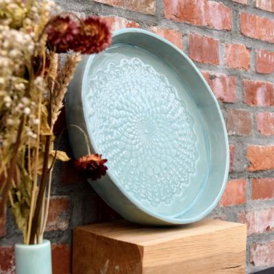 Eén ronde schaal in klei met een decoratieve afdruk.