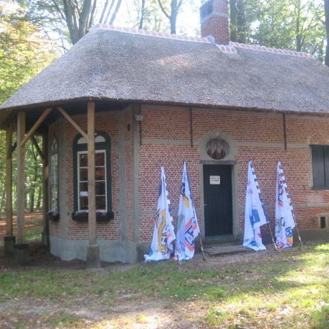 Een oude, kleine boswachterswoning met een rieten dak.